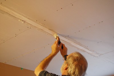 pressing drywall tape into a drywall seam